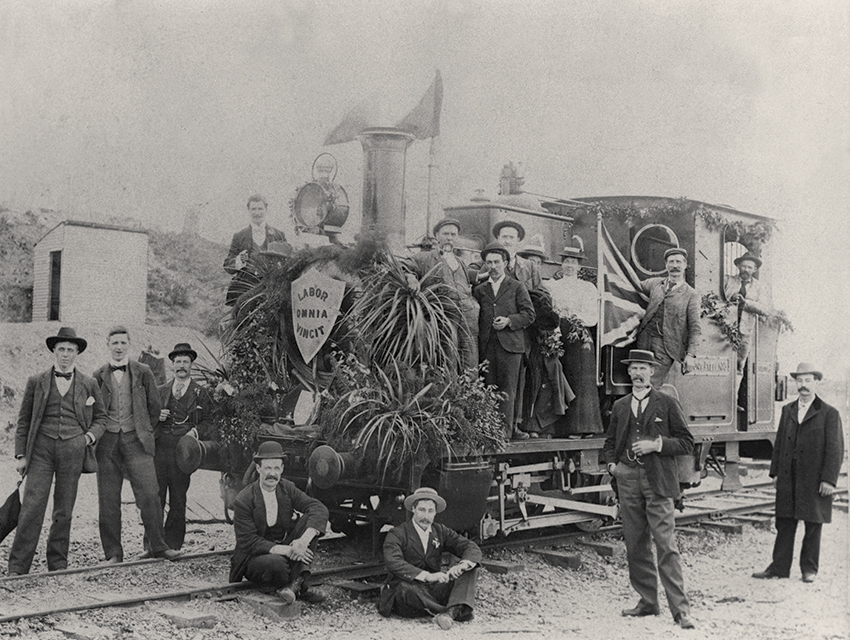 A group of workers huddles around a decorated locomotive